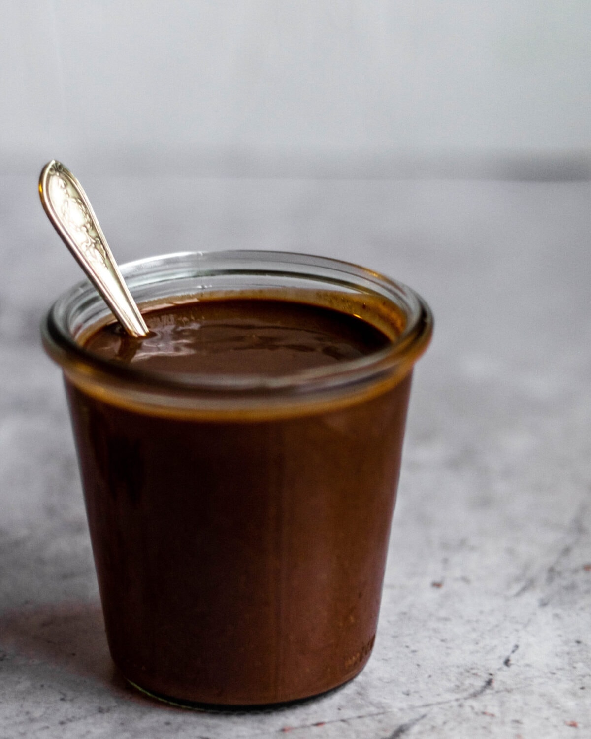 A jar of the chocolate hazelnut spread (nutella) with a spoon in it.