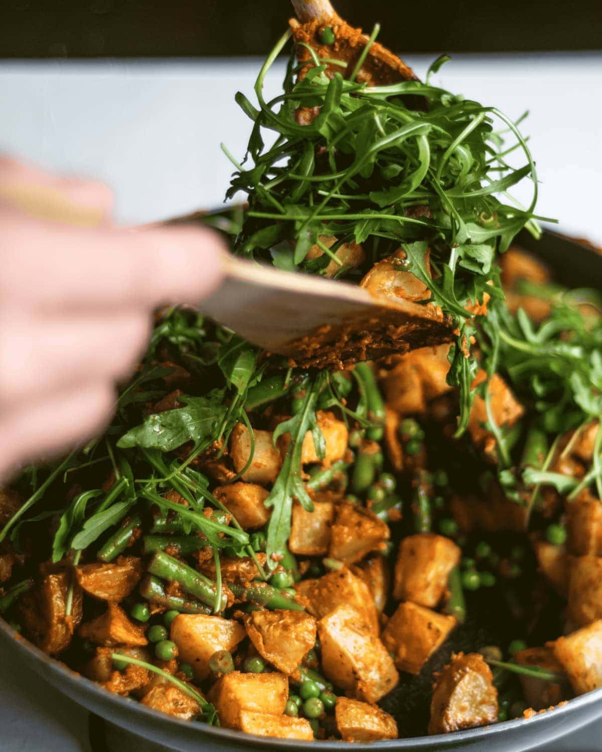 All of the cooked components being tossed together with some rocket.