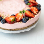 Strawberry cheesecake garnished with halved strawberries, blueberries and hemp seed.