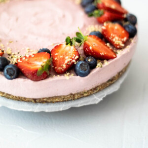 Strawberry cheesecake garnished with halved strawberries, blueberries and hemp seed.