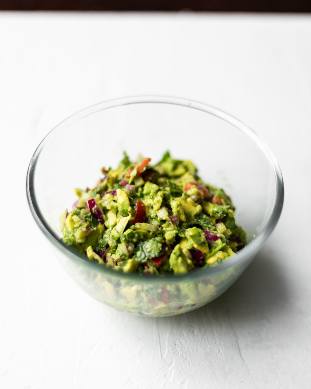 A glass bowl filled with guacamole.