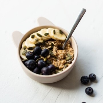 The finished bowl of weetabix based breakfast, topped with fresh blueberries, sliced banana and pumpkin seeds.