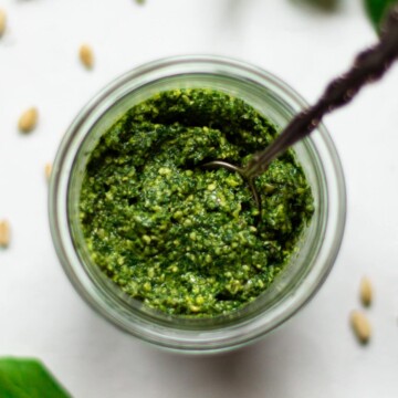 An overhead photo of the Vegan Pesto in a glass jar on a white background