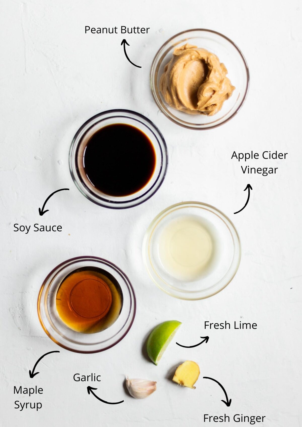Thai style vegan satay sauce ingredients laid out in glass bowls on a white background and labelled.