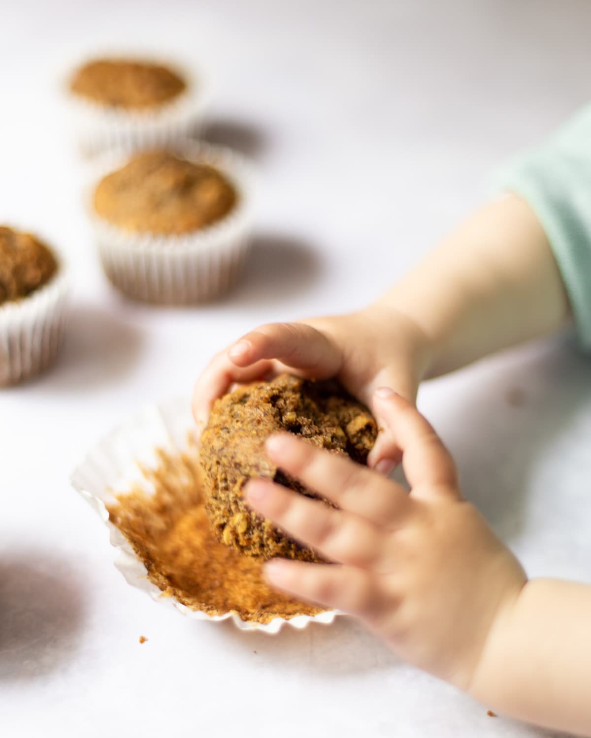 A toddlers grabbing one of the muffins before taking a bite.