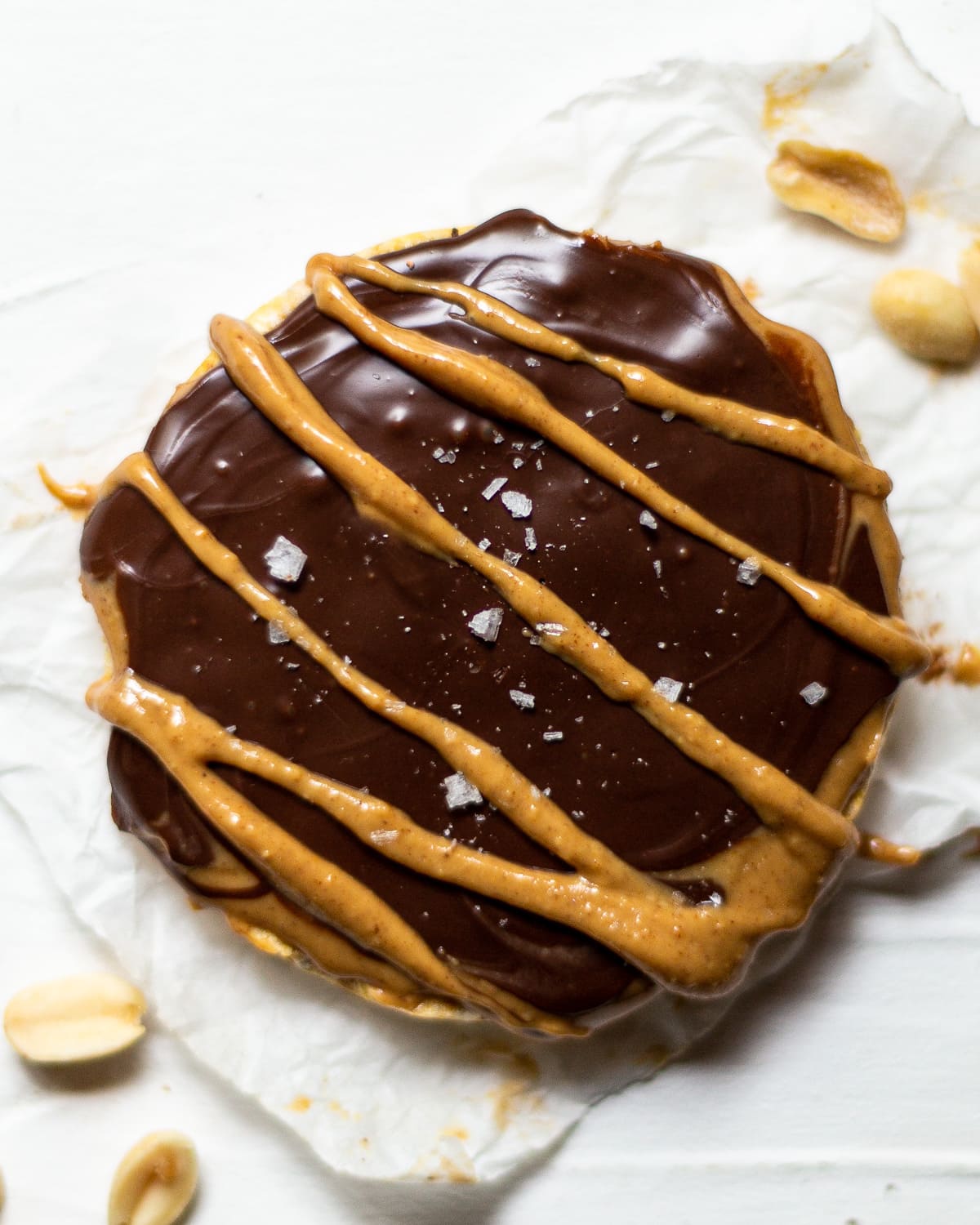 A rice cake, topped with peanut butter, melted chocolate and flaky sea salt.